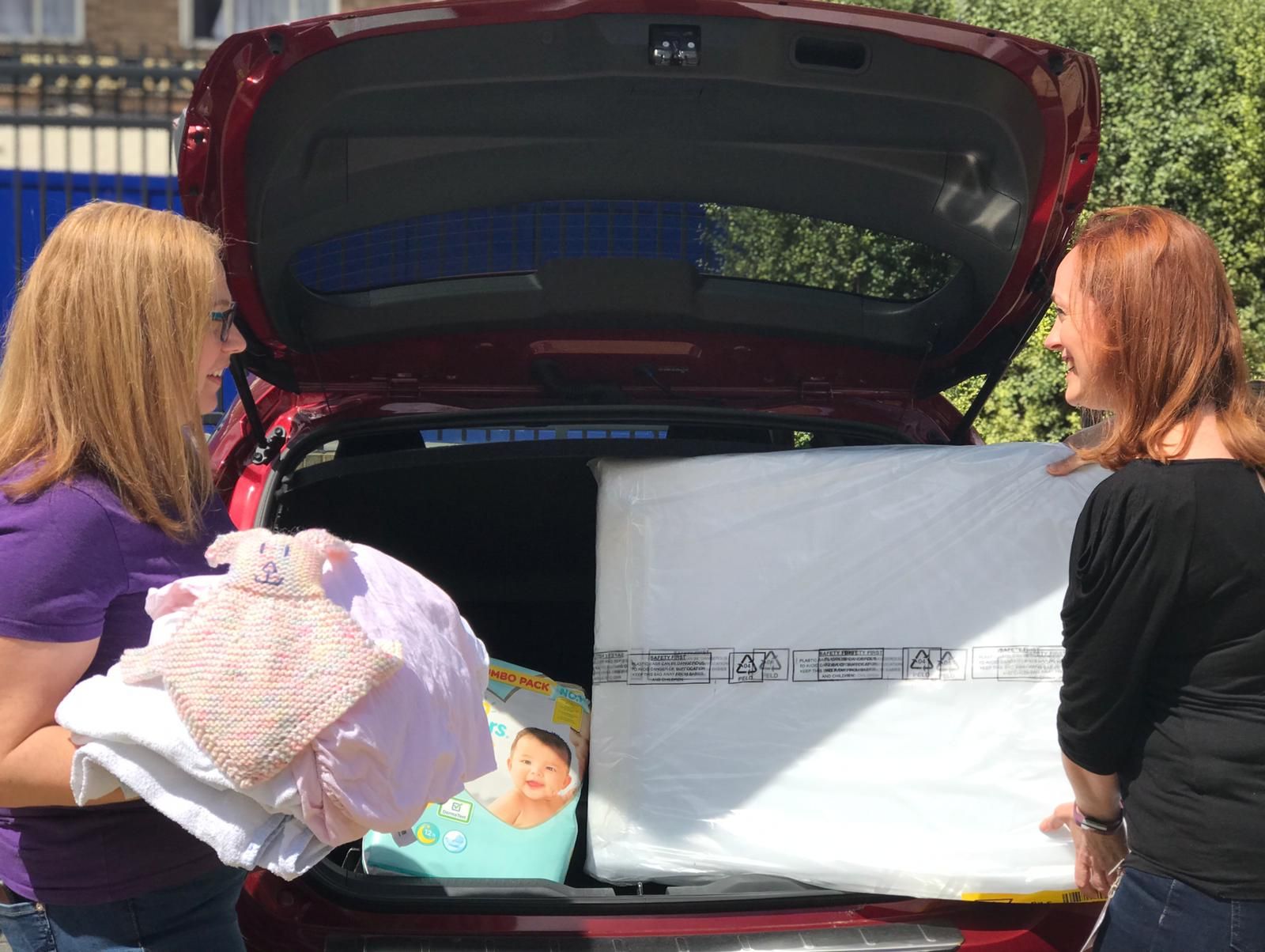 Two women loading gifts into the boot of a car