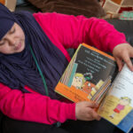 Lady in head scarf reading book to child