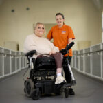 Lady in motorised wheelchair with nurse